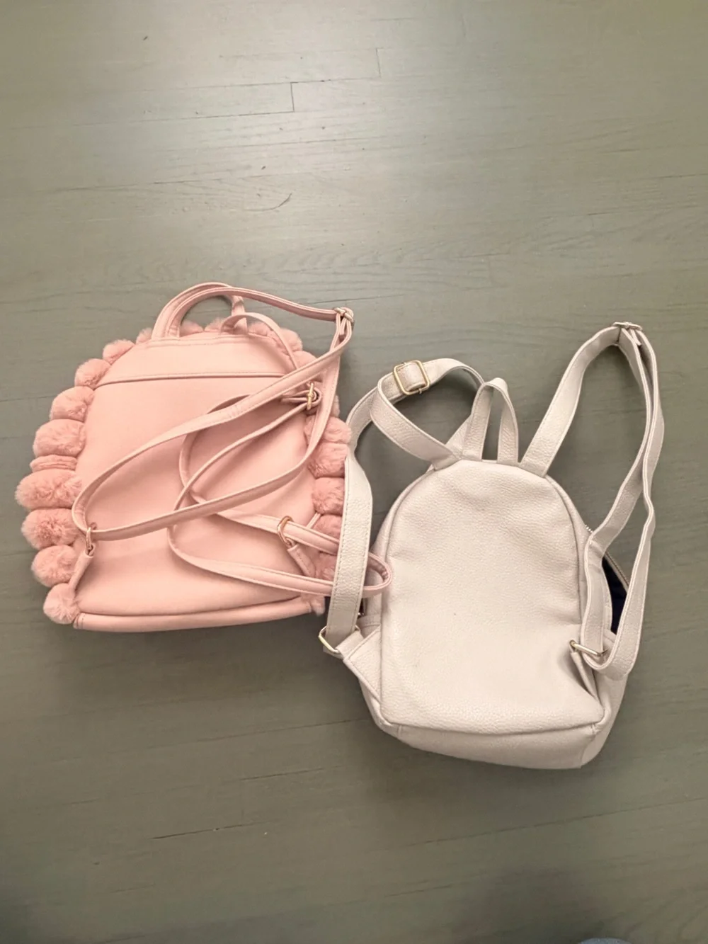 Two cute mini backpacks, one pink fuzzy, one white
